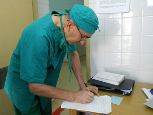 Father Aldo Marchesini processing paperwork in-between operating obstetric fistulas at Beira Central Hospital, in Mozambique.  Marchesini (left front),  operating with his team in Beira, has taught every surgeon who repairs obstetric fistulas in Mozambique. Credit: Mercedes Sayagues/IPS